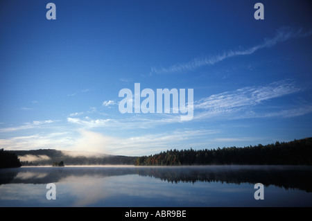 Le acque calme che riflette il cielo e i colori dell'autunno sulle sponde di un lago in Canada Foto Stock