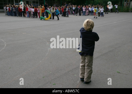 Un ragazzo solitario alla fine di playtime guarda i suoi amici andare a scuola, Stoke Newington, Londra, Regno Unito. Foto Stock