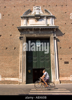 Gli uomini equitazione biciclette passano porta di ingresso alla Chiesa Catterdrale Duomo sulla strada principale di Chioggia Italia Foto Stock