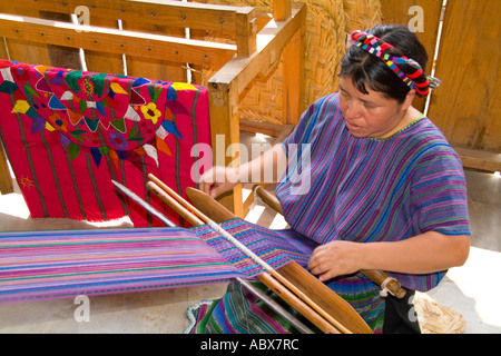 Donna al telaio per la tessitura artwork a mano di tessuti in un colorato abito in San Antonio sul telecomando lago Atitlan in Guatemala Foto Stock