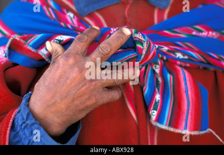 Close up di mani e scialle legato attorno al rosso poncho di una lingua Quechua uomo Tarabuco mercato domenicale Bolivia S America Foto Stock