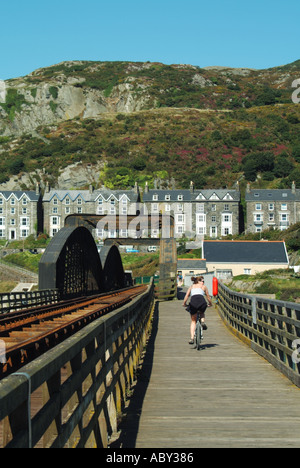 Ponte ferroviario Afon Mawddach e sentiero ciclabile a piedi collegamento Morfa Mawddach lato dell'estuario lady bike rider pedalando a Barmouth Galles del Nord UK Foto Stock