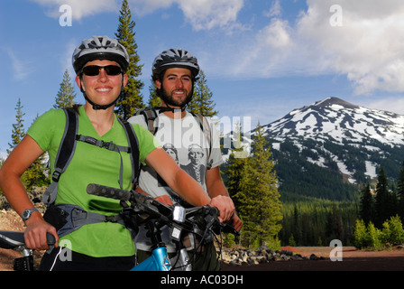 Sorridendo i ciclisti di montagna vicino a Snow capped Mount Bachelor Oregon USA Foto Stock