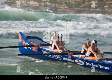 Una femmina surfboat equipaggio righe la loro barca in surf a Bondi Beach a Sydney Surfboats erano una volta usati per la spiaggia di salvataggio Foto Stock