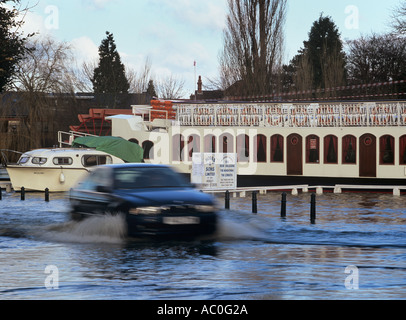 Auto mobile attraverso la strada allagata la terrazza sul fiume in piena dal fiume Tamigi Henley on Thames Oxfordshire Inghilterra Foto Stock