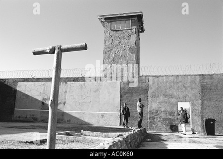 Gli uomini in piedi in esercizio cortile con la torre di avvistamento di Robben Island Cape Town Sudafrica Foto Stock