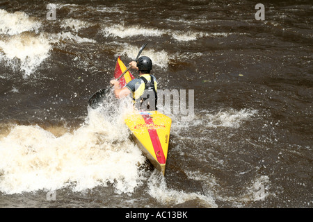 Un kayak si muove attraverso le turbolente acque di un fiume a Karlovy Vary, mostrando abilità e concentrazione in un kayak giallo brillante e rosso. Foto Stock