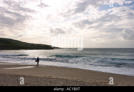 Un surfista guarda oltre le ultime onde del giorno sulla spiaggia Porthmeor, St. Ives. Foto Stock