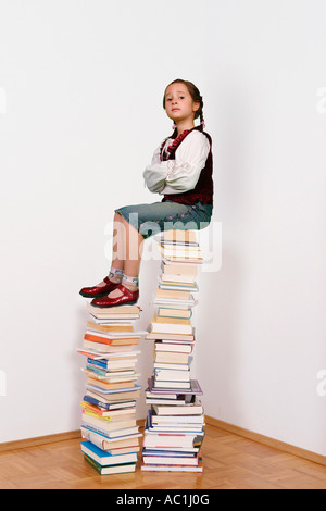 Ragazza con trecce seduti sulla pila di libri Foto Stock