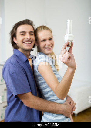 Giovane abbracciando, donna tenendo la lampadina Foto Stock