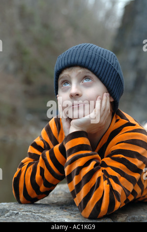 Ragazzo che guarda verso l'alto con il cappello in inverno, close up Foto Stock