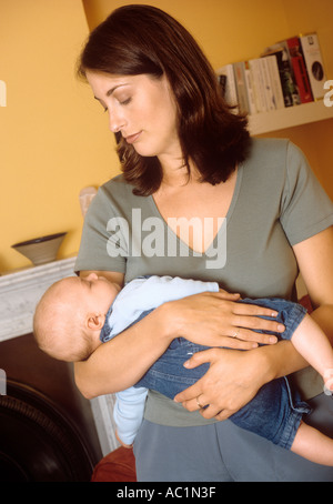 Madre DONDOLO BAMBINO suo figlio a dormire Foto Stock