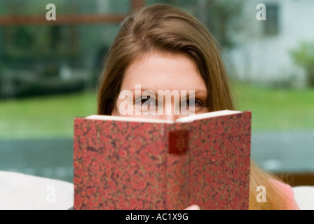 Giovane donna con libro uno scintillio nel suo occhio Foto Stock