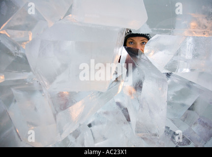 Una donna che guarda attraverso un foro in un muro costruito con i blocchi di ghiaccio in Jukkasjarvi ice hotel Foto Stock