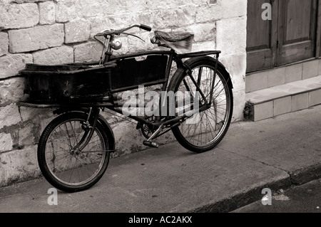 Vecchia bicicletta appoggiata contro un muro di pietra il commercio moto retrò Vintage Foto Stock