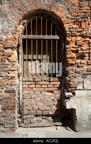 Vecchio di legno finestra incorniciata con weathered barre di acciaio per la sostituzione della porta in mattoni rossi con intonaco rimosso Cracovia Foto Stock
