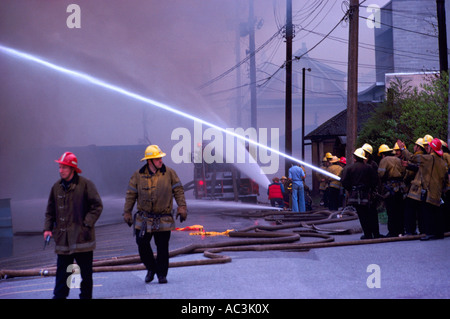 Vigili del fuoco / Vigili del Fuoco scontri a fuoco con tubo flessibile e acqua Foto Stock