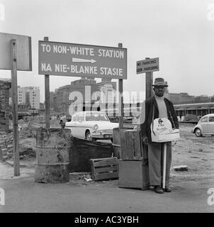 L Apartheid 1967 a Città del Capo con il mendicante cieco uomo in piedi da firmare in massa di rifiuti che indica di non stazione bianco Foto Stock