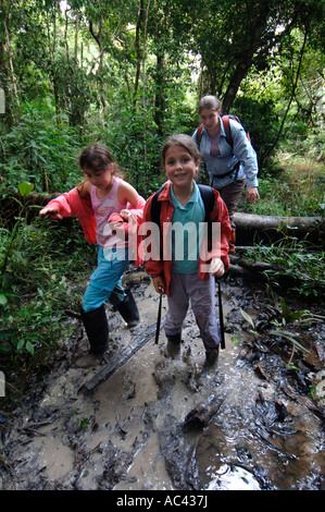 Il Perù avventura di vacanza American ragazze tromp attraverso il fango sul sentiero della foresta pluviale in vacanza a Tuhuayo Lodge Foto Stock