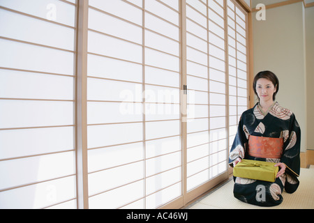 Giovane donna in kimono seduto sul pavimento Foto Stock