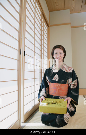 Giovane donna in kimono seduto sul pavimento Foto Stock