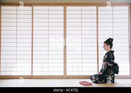 Giovane donna in kimono seduto sul pavimento Foto Stock