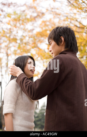 Giovane uomo prendendo foglia dalla ragazza capelli s Foto Stock