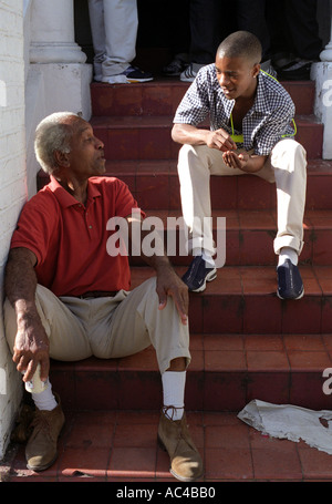 Due uomini seduti sulla soglia di casa in chat. Foto Stock