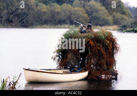 Un tiratore in una pelle alla Duck Shoot sulle sponde di un lago in Irlanda Foto Stock