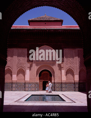 Due persone nel cortile con piscina visto attraverso un arco la madrasa di Ali ben Yusuf Marrakech marocco Foto Stock