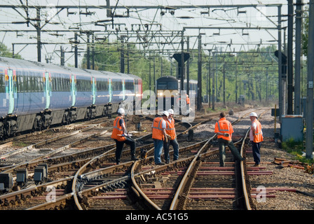 La linea ferroviaria principale di Liverpool Street per East Anglia, gli addetti alla manutenzione dei binari ad alta visibilità lavorano accanto ai treni alla stazione di Shenfield, Essex, Inghilterra, Regno Unito Foto Stock