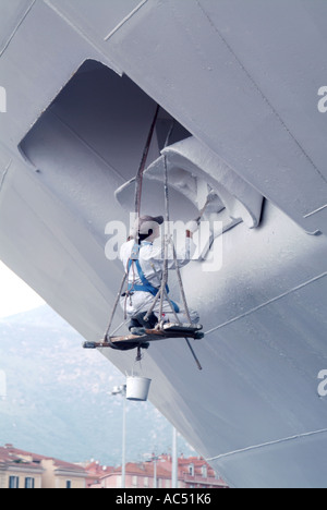 Ajaccio area portuale uomo al lavoro su strette listone verniciatura carter di ancoraggio di ormeggiata la nave di crociera Foto Stock