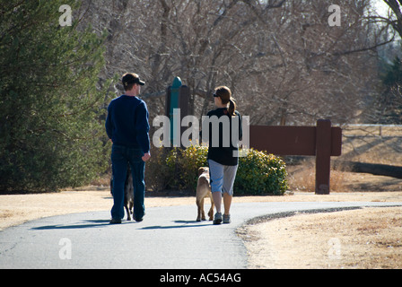 Uomo caucasico e donna camminando due cani su un sentiero a piedi nella città di Oklahoma, Oklahoma, Stati Uniti d'America. Foto Stock
