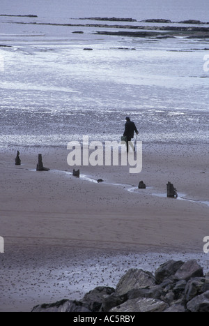 Un beachcomber cercando articoli lavati fino dalle maree sulla West Somerset costa vicino Watchet Foto Stock