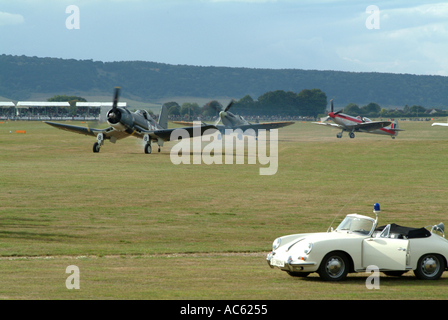 Corsair FG 1D Chance Vought e due Spitfires preparando per decollare con corso Porsche auto a Goodwood 2003 Sussex Foto Stock