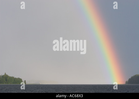 La fine dell'arcobaleno colpendo sputo di terra in un lago , Finlandia Foto Stock