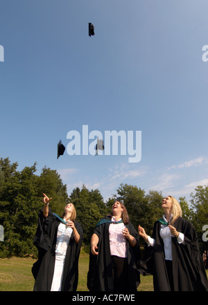 Tre studenti donne gettando la loro scheda di mortaio tappi in aria dopo la laurea dall'Università di Aberystwyth Wales UK Foto Stock