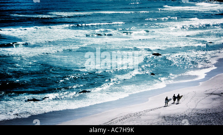 Tre i surfisti a piedi lungo il lungomare Foto Stock