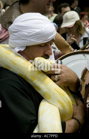 Uomo in bianco turbante kissing grande giallo python durante il mercato medievale, Balmaseda, Paesi Baschi, l'Europa. Foto Stock