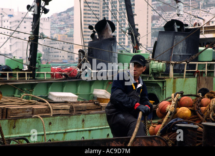 Un pescatore su una barca da pesca vicino Jagalchi fishmarket nel porto di Busan, Corea del Sud Foto Stock