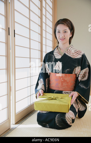 Giovane donna in kimono seduto sul pavimento Foto Stock