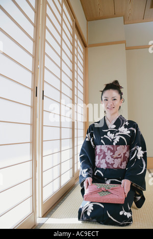 Giovane donna in kimono seduto sul pavimento Foto Stock