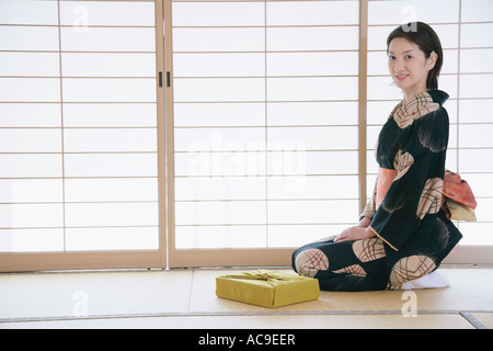 Giovane donna in kimono seduto sul pavimento Foto Stock