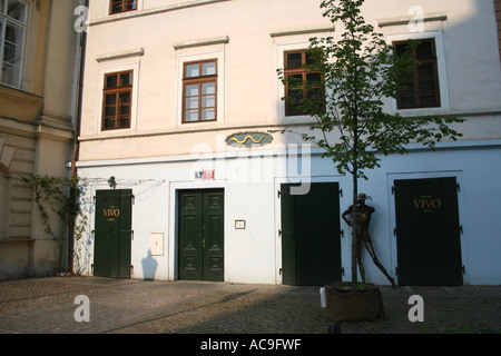 Caffè chiuso a Praga al mattino con porte e finestre verdi, con una statua e un piccolo albero di fronte. Foto Stock