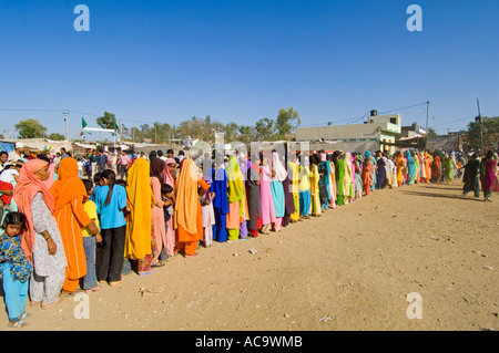 Una lunga coda di donne e ragazze vestiti nei loro vestiti migliori aspettando pazientemente che il cibo gratuito presso il festival di Mewar. Foto Stock