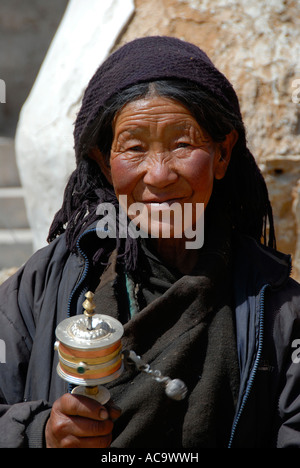 Ritratto di donna tibetana oscilla una ruota di preghiera Tibet Cina Foto Stock