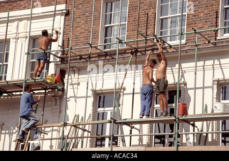 Guildford Surrey scaffolders lavorando su acciaio ponteggio tubolare eretta alla faccia dell'edificio per lavori di manutenzione per continuare Foto Stock