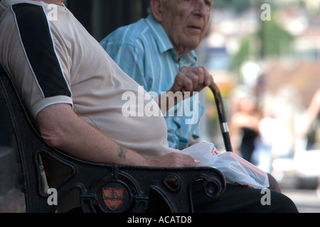 Due uomini anziani su un banco di lavoro con una grande pancia Foto Stock