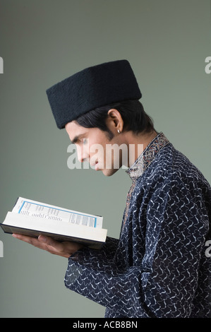 Profilo laterale di un giovane uomo di leggere il Corano Foto Stock