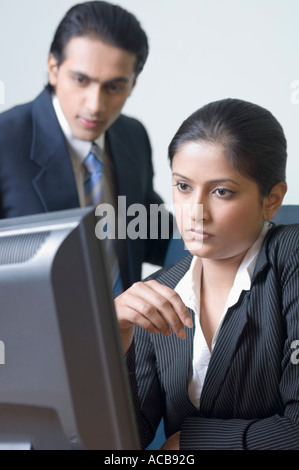 Imprenditrice e un imprenditore in cerca di un computer Foto Stock